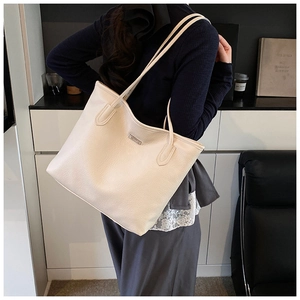 Detailed view of the pebble grain texture and logo on this cream tote bag for women