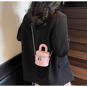 Pink mini cylinder bucket bag with double zippers and silver chain on black blazer