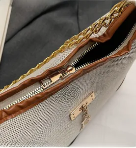 Detail of white woven fabric, brown leather trim and smooth gold metal zipper closure