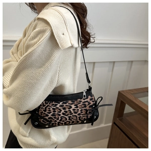 Detail view of leopard print shoulder bag with silver studs and black side bows