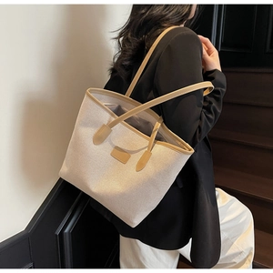 Detail view of large straw tote bag with brown leather straps and beige woven fabric