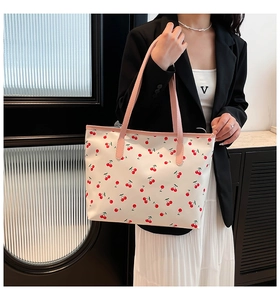 Detail of cute bear tote bag with cherry print and pink handles shown on a model