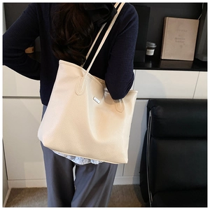 Détail du grand sac cabas crème avec texture grainée et plaque métallique de logo