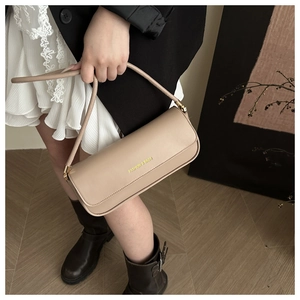 Detail of beige faux leather baguette bag with FASHION & BAGS print and gold metal hardware