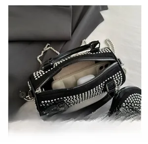 Detail showing internal capacity of studded cylinder bag with smartphone and earbuds