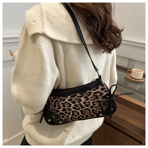 Leopard print shoulder bag with black leather straps and side bow detail on a model