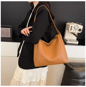 Close-up of a large brown matte leather hobo tote bag worn as a shoulder bag