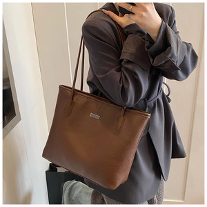 Brown lychee grain leather tote bag shown in a mirror selfie highlighting large capacity