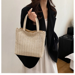 Detailed herringbone weave texture on a beige straw tote bag with white leather handle