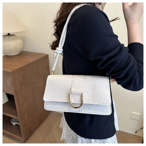 Détail du sac blanc tressé avec boucle dorée en fer à cheval et bandoulière nouée
