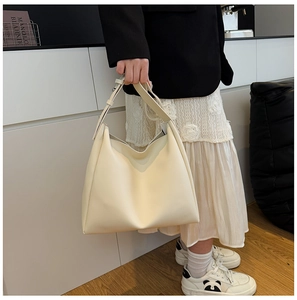 Detail of adjustable metal buckle on shoulder strap of a creamy white leather tote bag