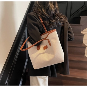 Chic beige canvas tote bag with brown leather trim shown on shoulder in urban setting