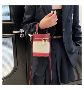 Red leather and beige canvas bucket bag shown on a model in a modern lifestyle setting