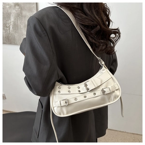 Detail of cream shoulder bag with silver metal buckles and punk-style straps