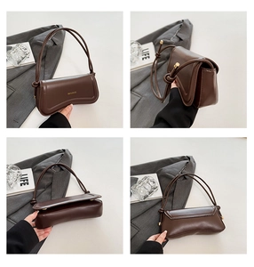 Detail view of coffee brown leather underarm bag with knot strap and gold lettering