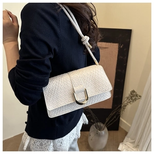Détail du sac à main en cuir gaufré blanc avec fermoir en U doré et bandoulière nouée