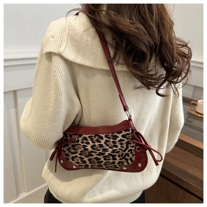Detail of leopard print shoulder bag with red trim, bow accent and silver studs