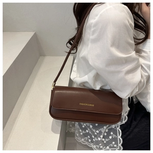 Close-up of brown baguette bag with golden 'FASHION & BAGS' text and smooth leather