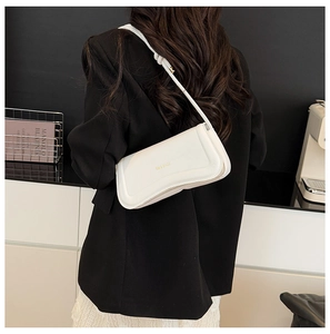 Close-up of white leather flap shoulder bag with gold logo on black blazer background