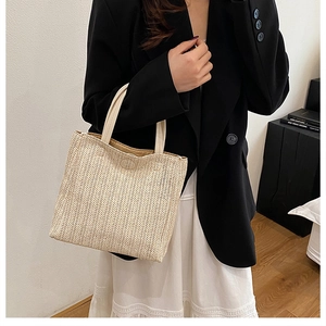 Detail of handwoven beige tote bag with premium leather handle and herringbone pattern
