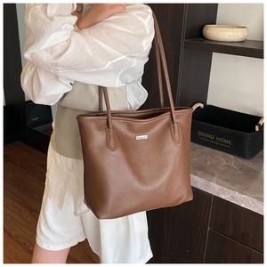 Gros plan sur un sac cabas en cuir marron avec texture grainée et logo métallique chic