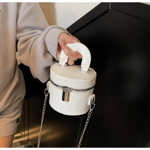 Detail of white mini bucket bag with dual zippers and silver chain shoulder strap