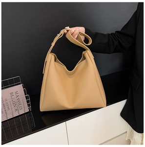 Detail view of khaki leather tote bag featuring adjustable strap and metal hardware details