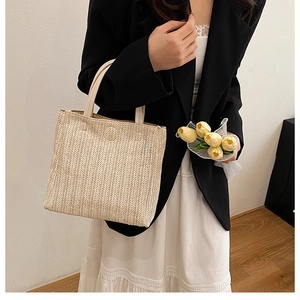 Detail of hand-woven beige straw tote bag with V-shaped texture and leather handles