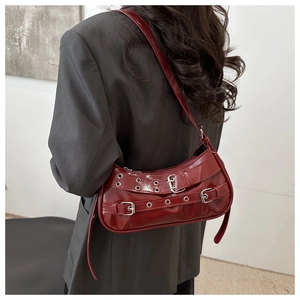 Detail of burgundy Y2K punk shoulder bag with metal eyelets and adjustable buckle straps