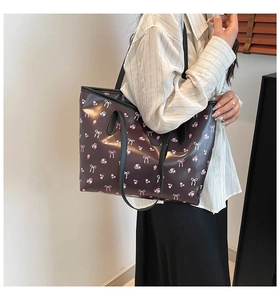 Detail of dark brown tote bag with pink floral patterns and decorative bows