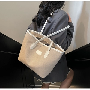 Detail view of the large canvas tote bag showing stitching and white leather trim