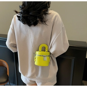 Detail of neon green mini bucket bag with double zippers and elegant chain strap