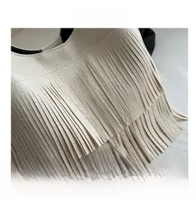 Close-up of cream faux leather bag featuring long stylish tassels and grainy texture