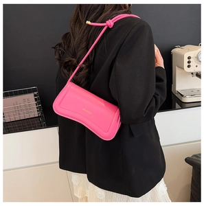 Close-up of bright pink leather shoulder bag with gold logo and knotted strap detail