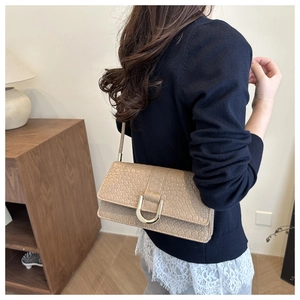 Détail du sac beige à relief crocodile avec boucle fer à cheval dorée et bandoulière fine
