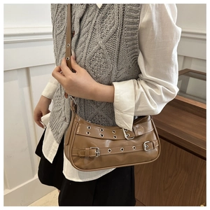 Detail of khaki shoulder bag with silver eyelets and buckle on vintage faux leather