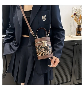 Detailed view of leopard print cylinder bucket bag with dual metal zippers and strap