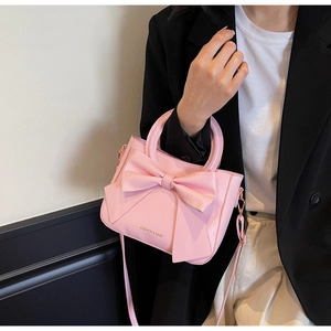 Close-up of pink bucket bag featuring a large decorative bow and top handle