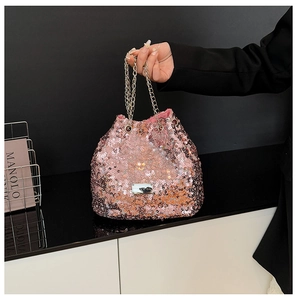 Detailed macro view of pink sequin bucket bag with elegant chain strap and metal logo plate