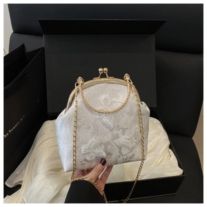 Detail of white lace handbag with butterfly embroidery and golden metal frame in a gift box