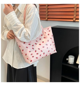 Pink strawberry pattern tote bag worn by a model in a minimalist modern interior