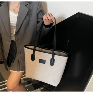 Detail of high-density canvas tote with black leather trim and structured strap