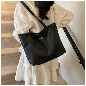 Détail du sac cabas noir en cuir grainé avec étiquette métallique argentée et surpiqûres