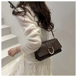 Gros plan du sac à main marron tissé avec boucle dorée en forme de U élégante