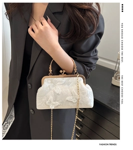 Close-up of white lace handbag with 3D butterfly embroidery and gold chain strap