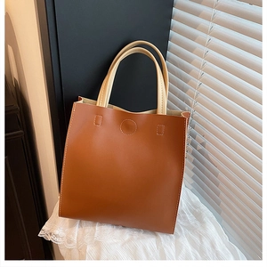 Detail of brown tote bag showing white contrast stitching and premium leather texture