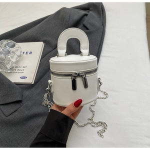 Macro shot of white cylinder bucket bag with dual zippers and silver chain detail