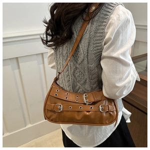 Detail of brown glossy leather shoulder bag with punk buckles and silver eyelets
