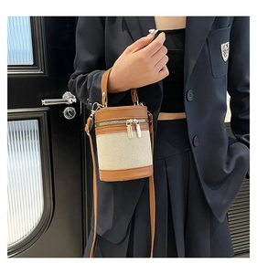 Detail view of contrast stitch bucket bag with canvas texture and gold hardware zipper