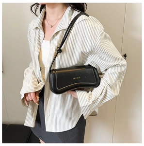 Detail of black leather shoulder bag with wavy bottom and gold XM & BAGS logo